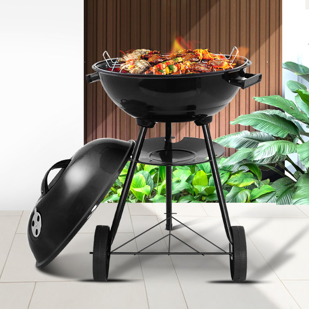 Black barbecue grill with food on a patio
