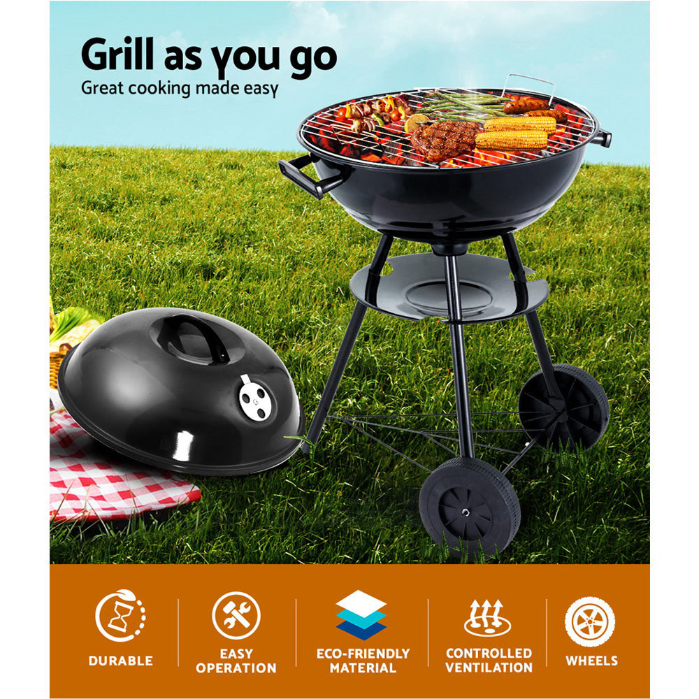 Portable grill with wheels on grass, featuring food being cooked