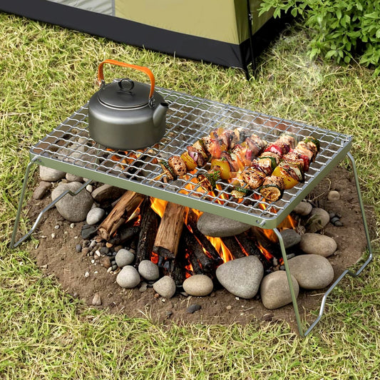 Outdoor grill with food and a kettle over a campfire on grass