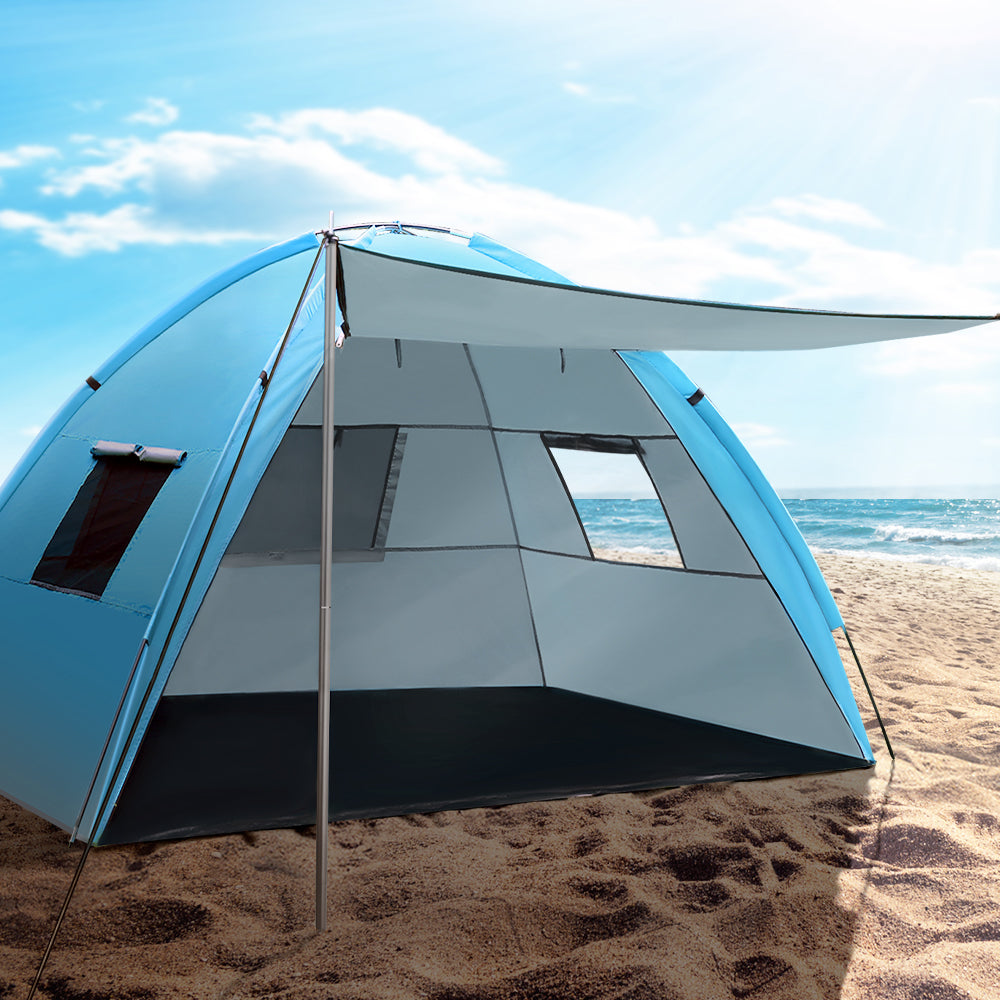 Blue and gray beach tent on a sandy beach with ocean view