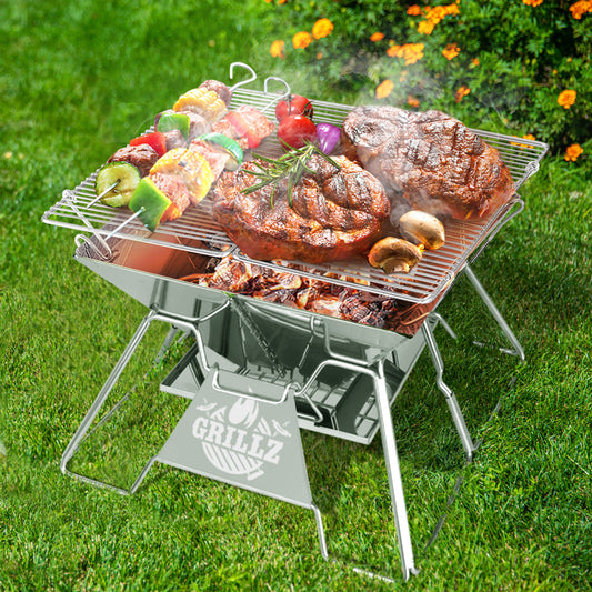 Portable grill with food on a grassy outdoor setting