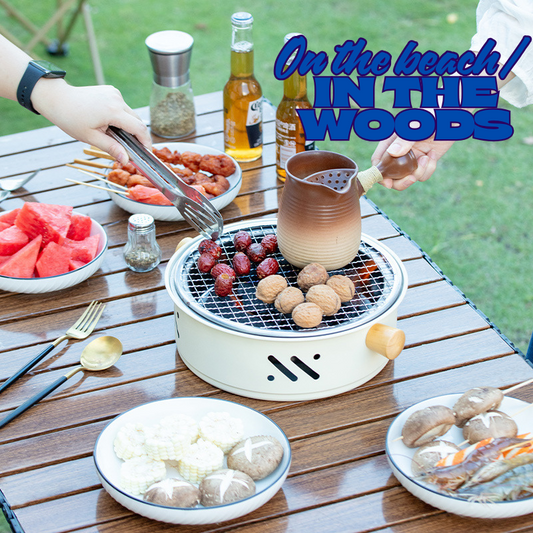 Outdoor picnic setup with a portable grill, food, and drinks on a wooden table.